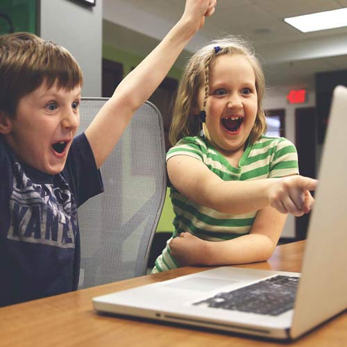 two kids looking at a computer screen without blue light glasses